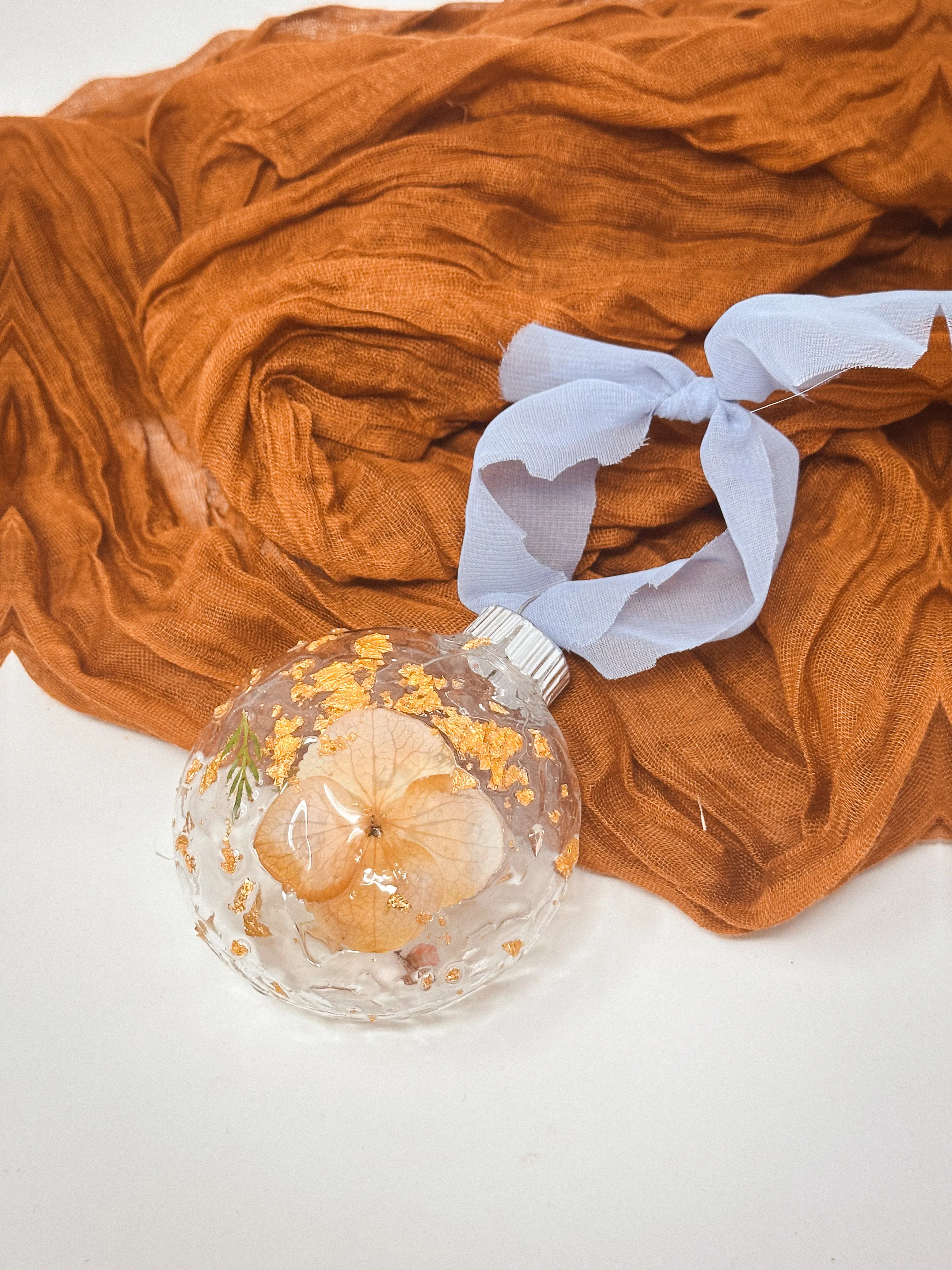 Real pressed flowers resined onto a plastic ball ornament.