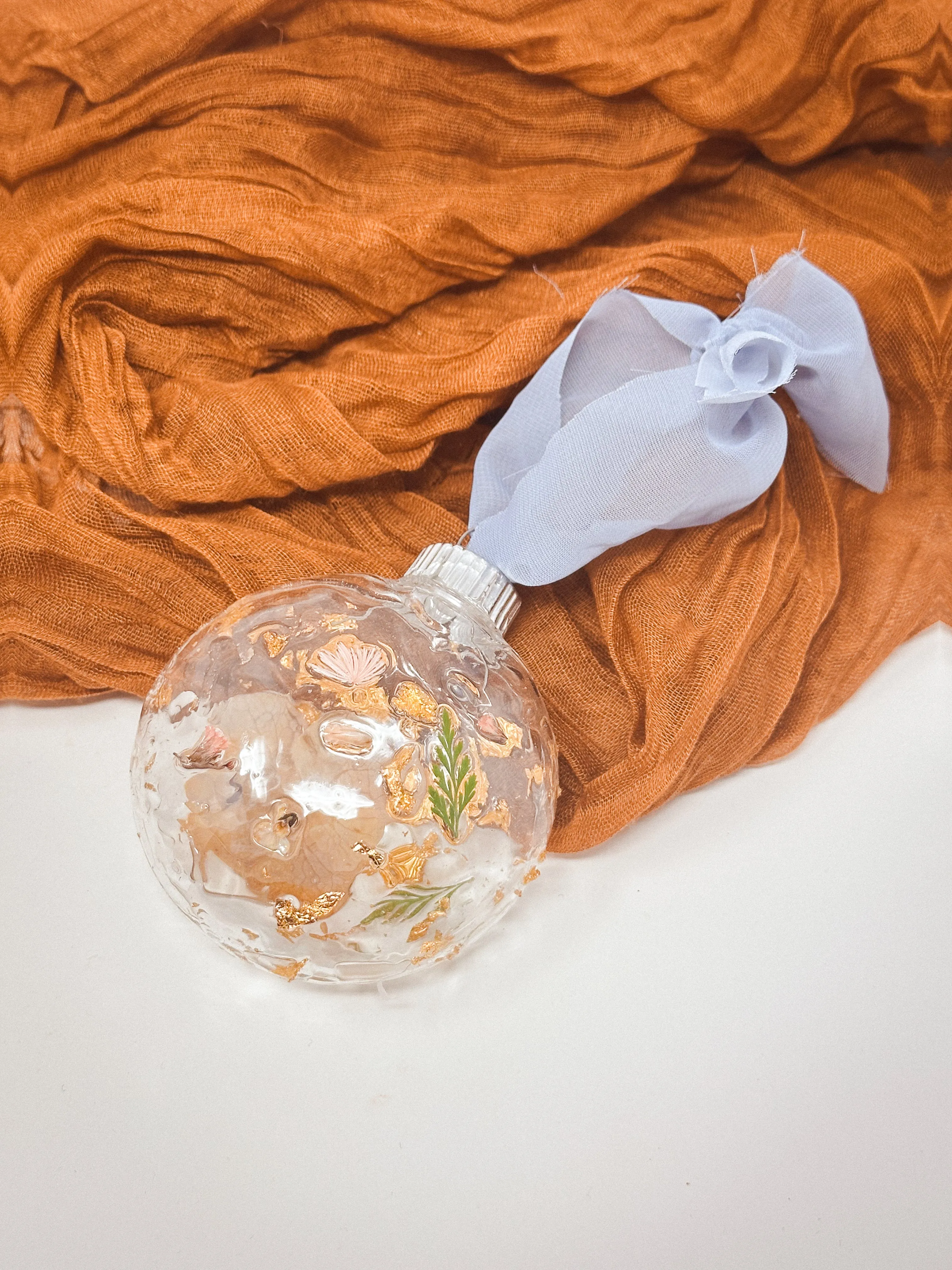 Real pressed flowers resined onto a plastic ball ornament.